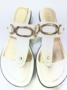 Unisa brand white mules featuring a gold-tone metal detail.